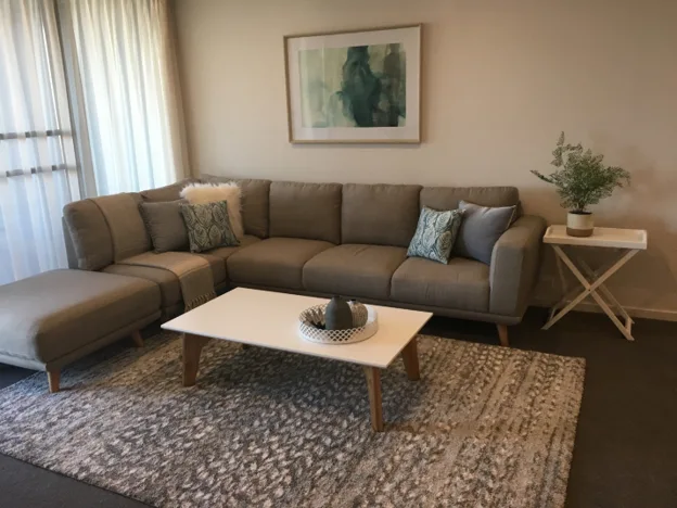 Living room interior with a sectional sofa, white coffee table, patterned rug. Home furniture package.